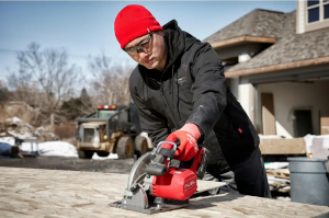man wearing jacket using saw outside