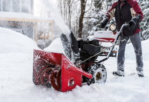 man pushing red snow blower