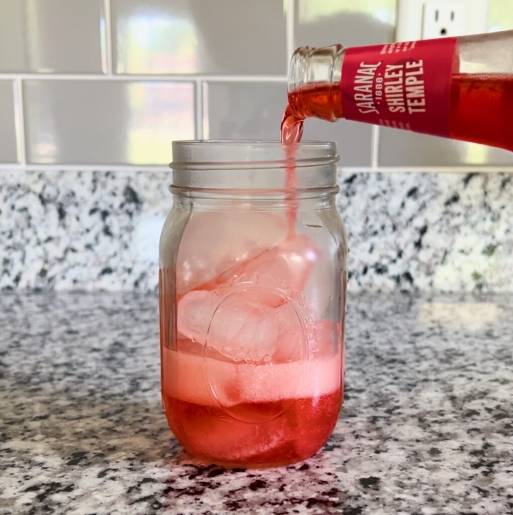 adding red soda to mason jar