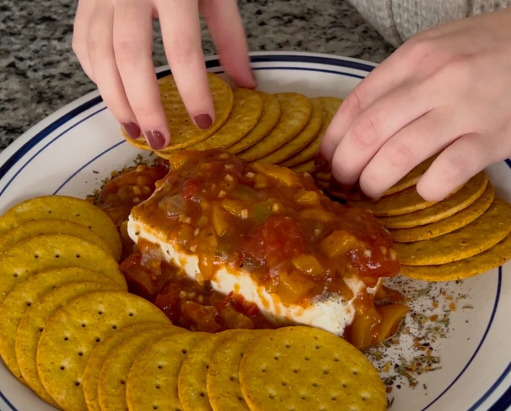 adding crackers around cheese dip