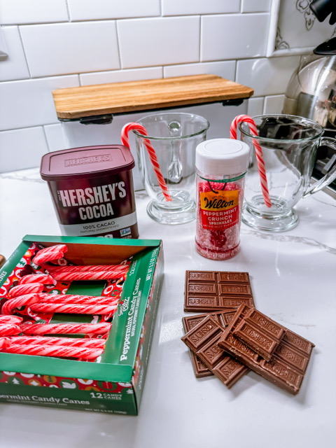 candy canes, cocoa powder, sprinkles, chocolate bars, and mugs on countertop
