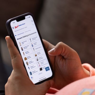 Woman holding phone shopping the Farm & Fleet Mobile App
